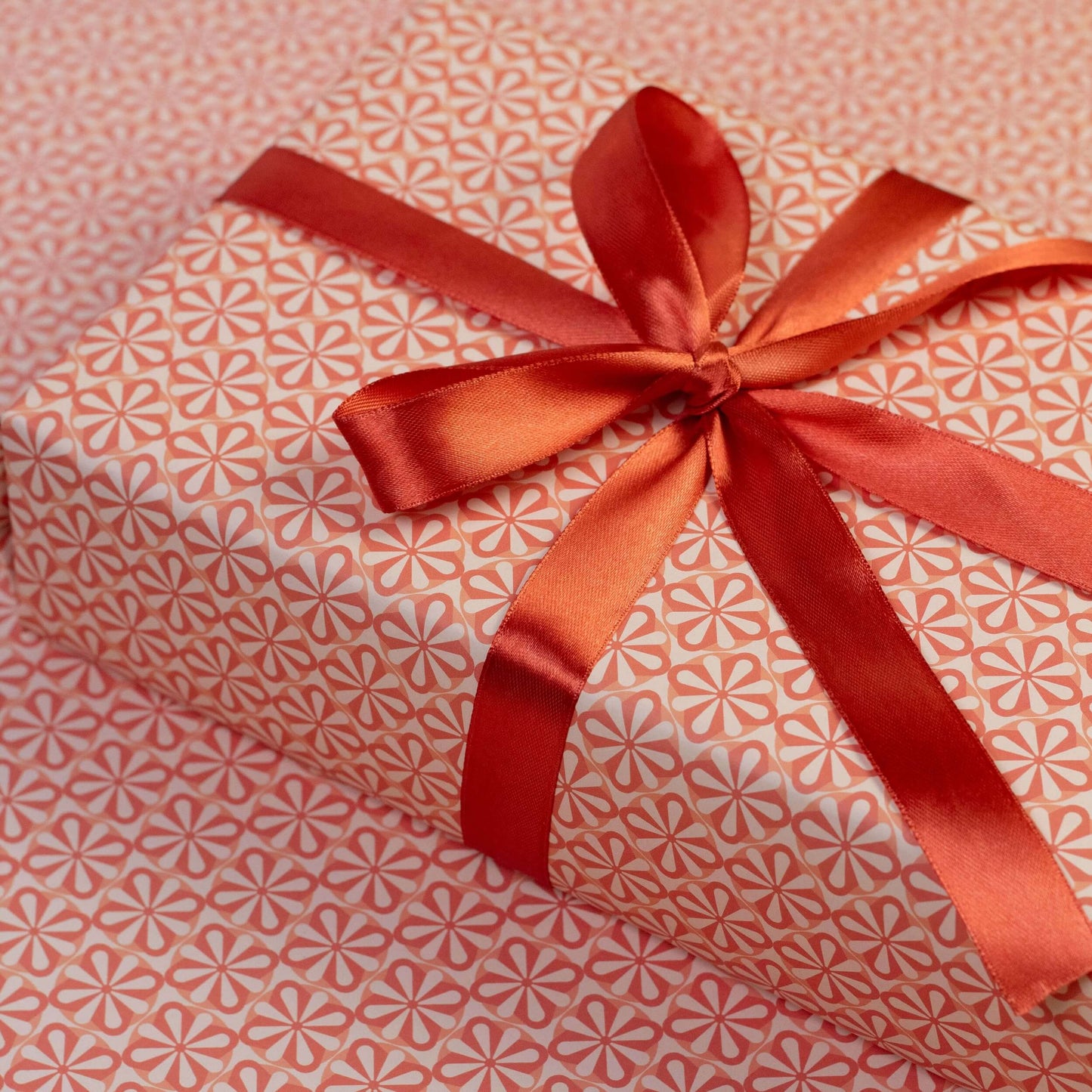 Gift wrapped in pink floral patterned paper with a red ribbon