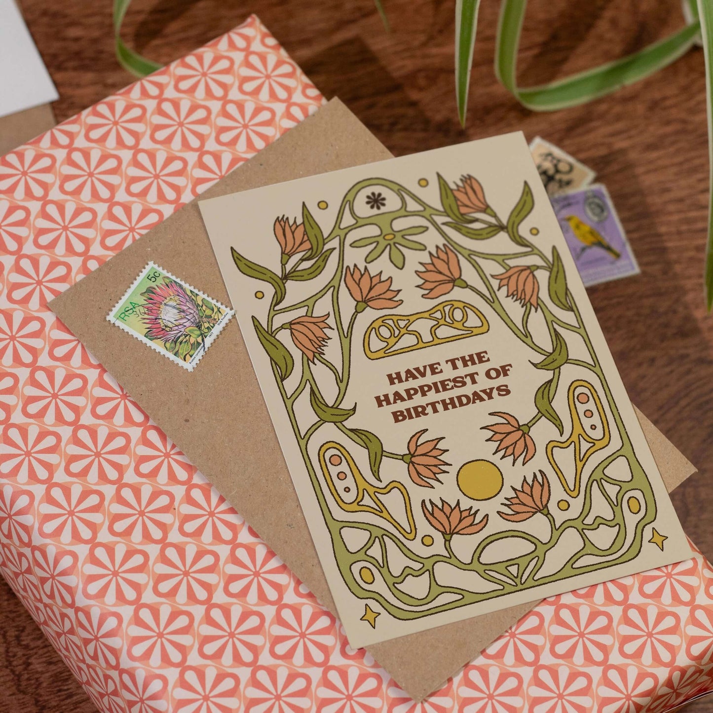 Greeting card with floral design and text on a gift wrapped in pink floral wrapping paper.