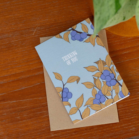 Greeting card with a plum tree design on a wooden surface