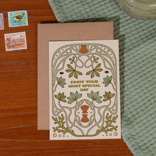 Wedding card with floral design and text reading 'Enjoy Your Most Special Day' on a wooden surface with stamps and fabric.