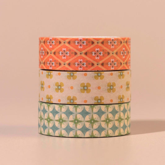 Three rolls of decorative tape with floral and star patterns on a beige background