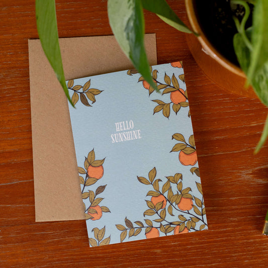 Card with 'Hello Sunshine' text and apricot tree design on a wooden surface