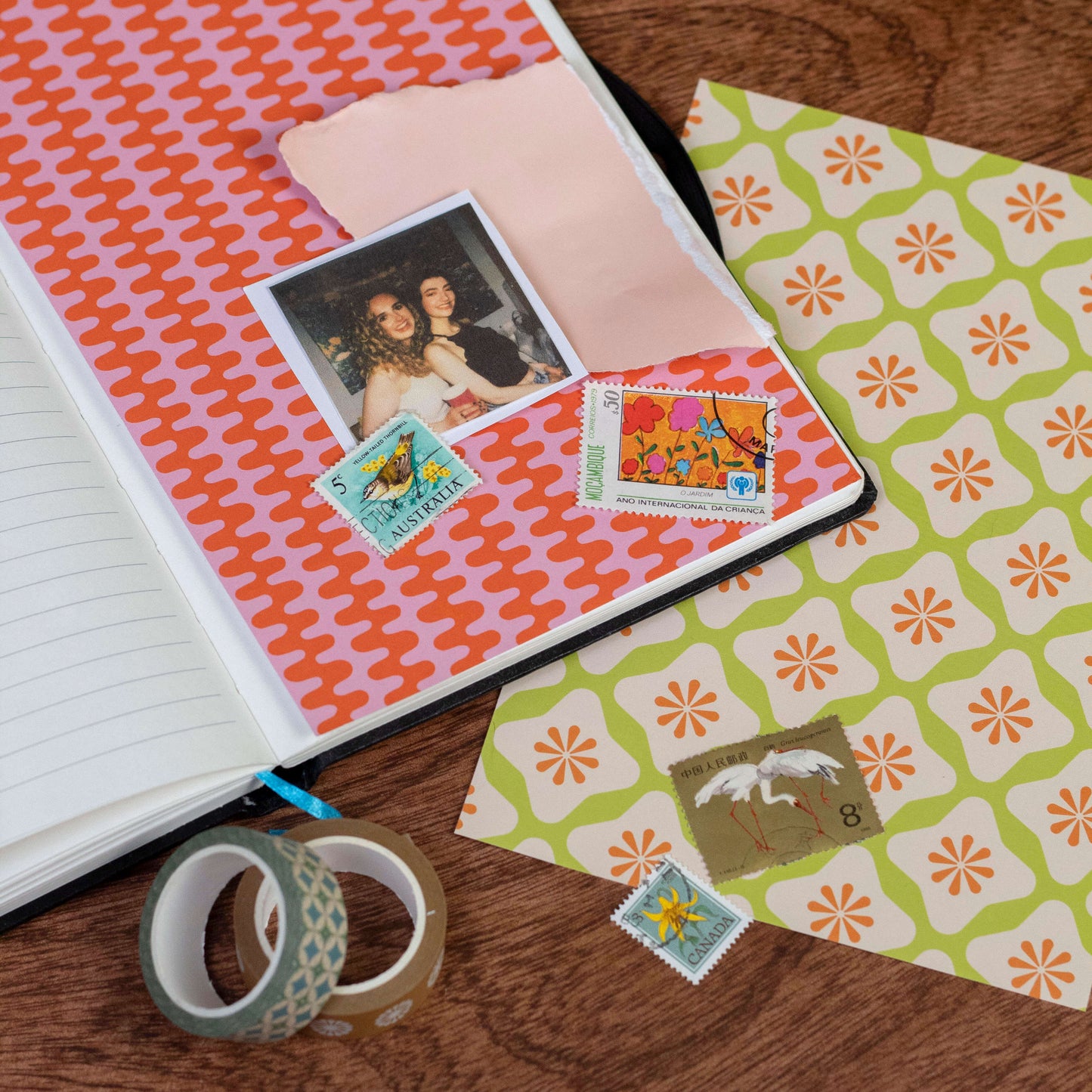 Open notebook with decorative craft papers and tape on a wooden surface