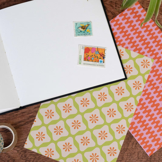 Patterned paper and blank notebooks with stamps on a wooden surface